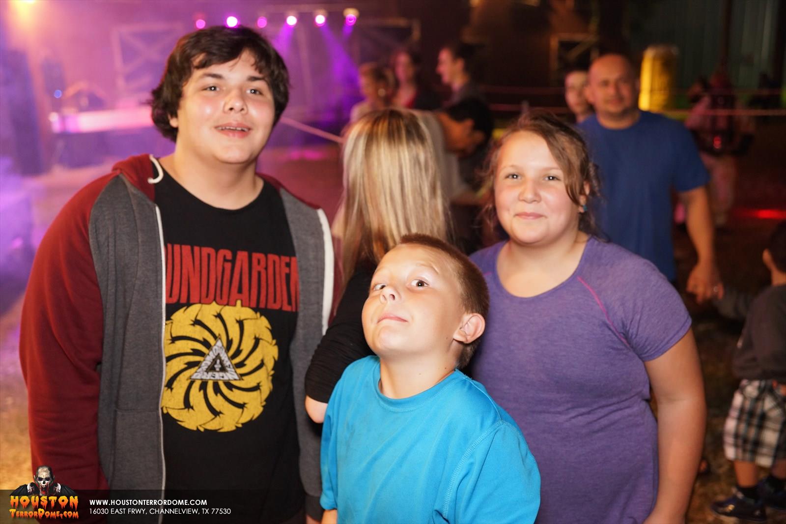Family waits in line, kid in blue shirt shows scary pose for camera
