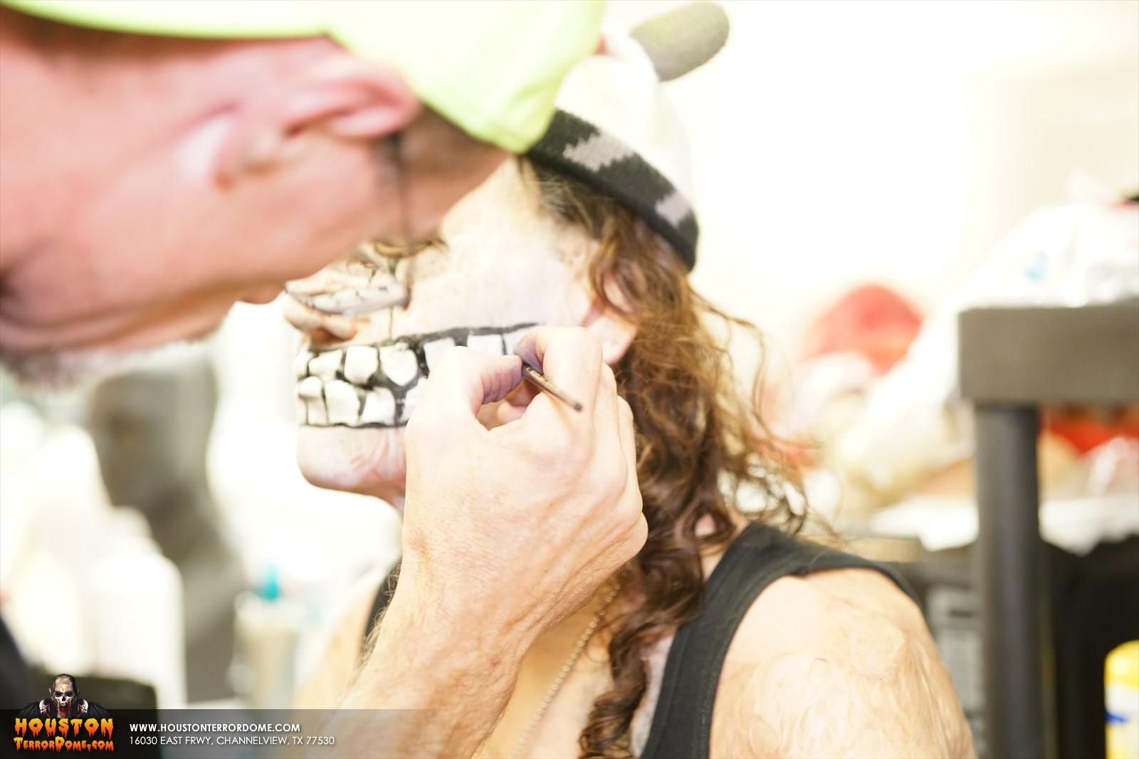 Makeup artist applying makeup to skull actor