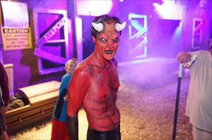 The Devil with full face paint out front of haunted house